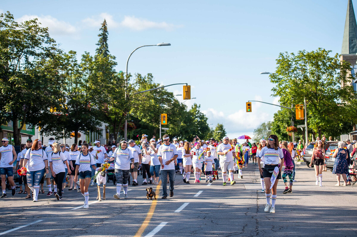 hundreds of marchers during the Tweed Canopy Growth pride parade in the street waving flags.  Captured by Ottawa Event Photographer JEMMAN Photography COMMERCIAL 