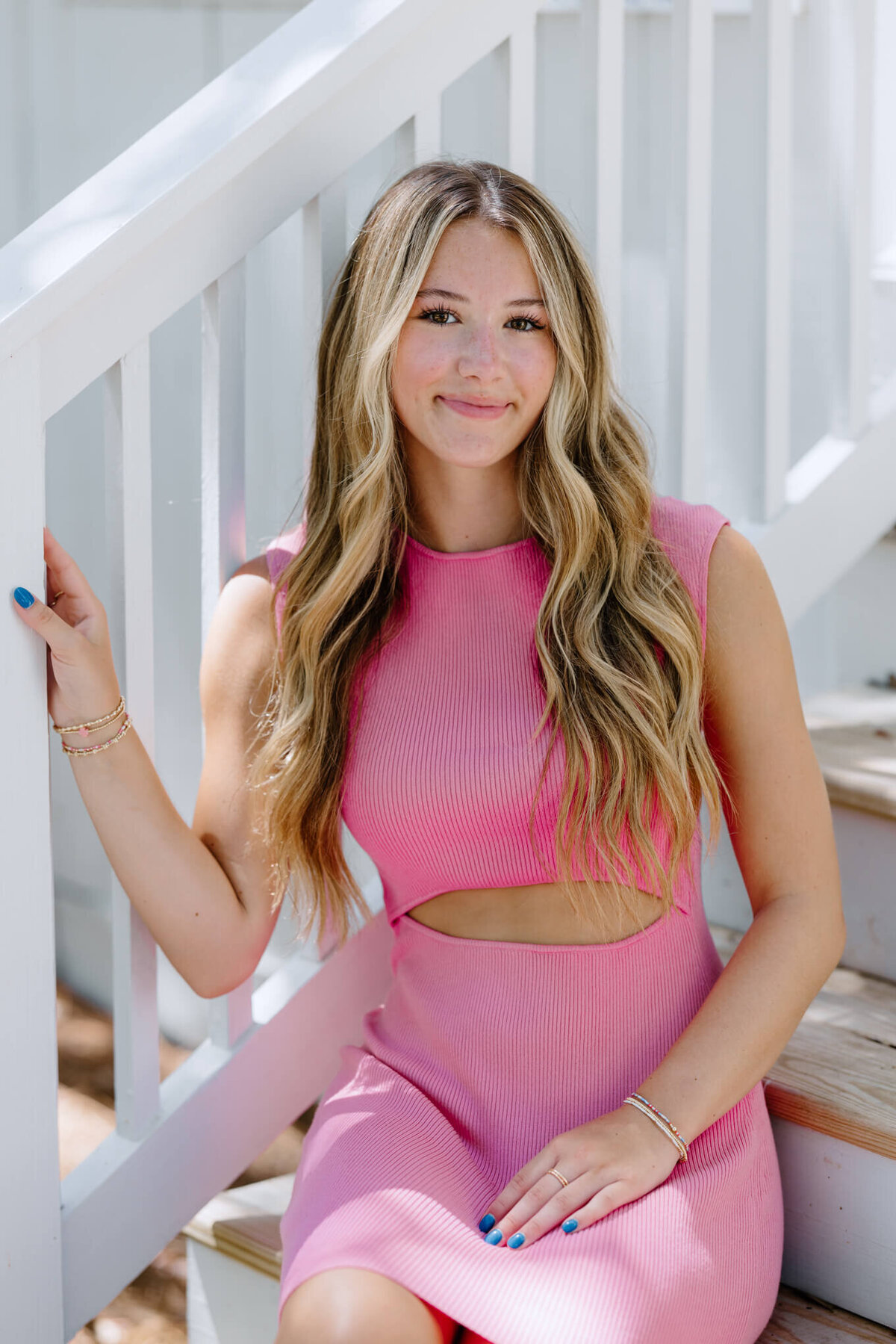 senior girl in light pink dress sitting on white steps in Seaside Florida