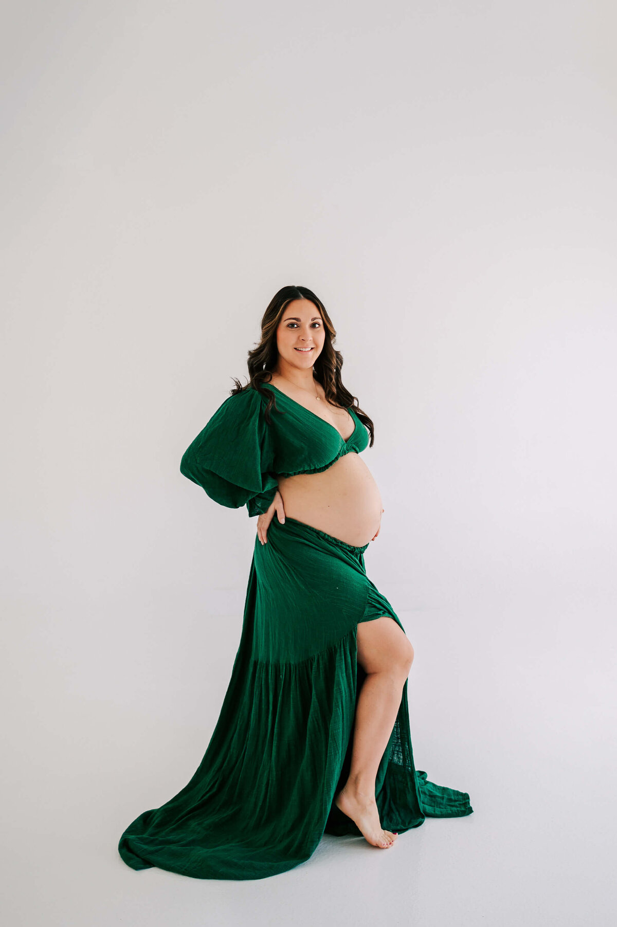 pregnant mom in green dress smiling during Joplin MO maternity photography session