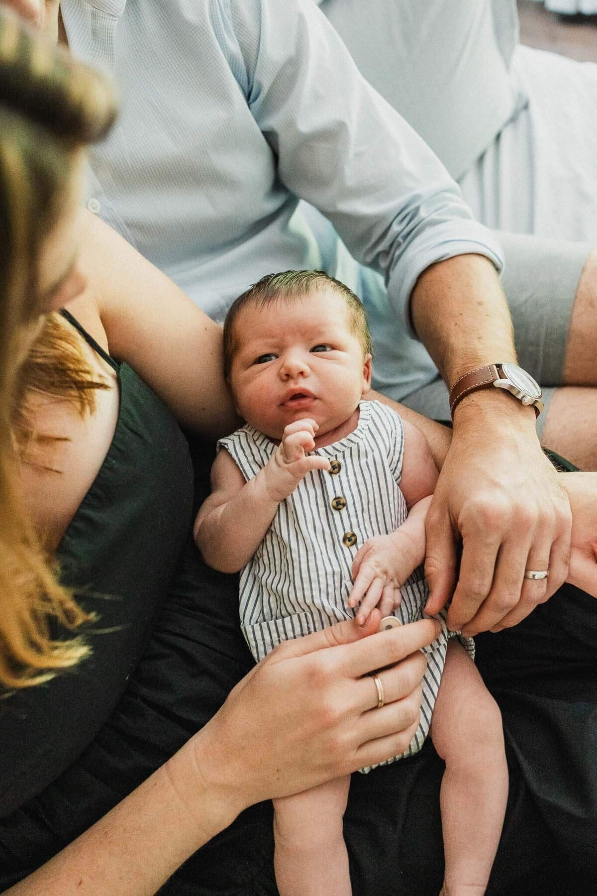 Newborn held by parents in an intimate family moment during Cleveland lifestyle photography session.