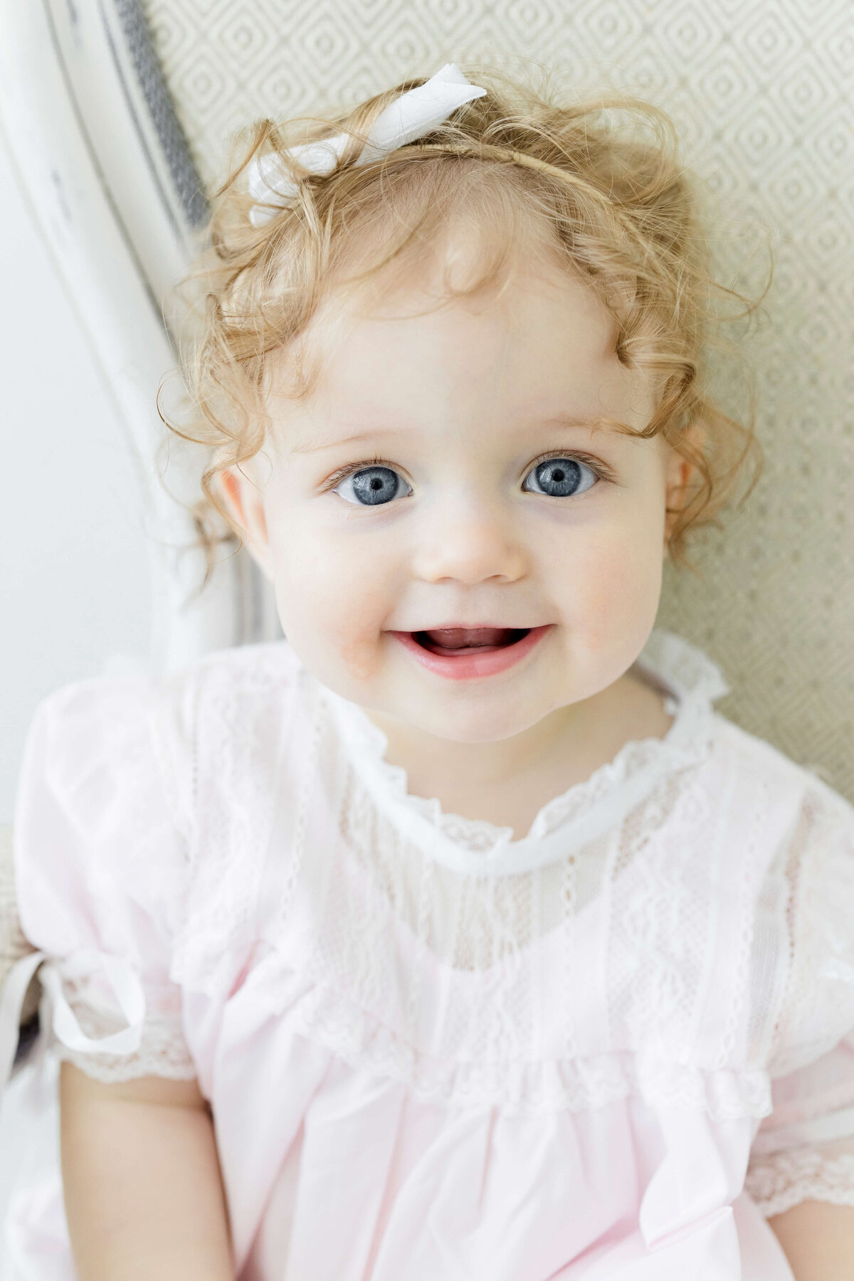 Baby girl sitting up in chair smiling for milestone photography