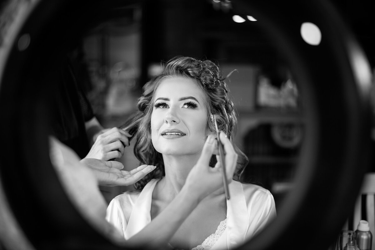 Black and white image of soon to be wife getting make up done by professional make up artist