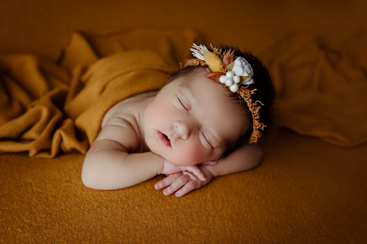 newborn girl in gold color blanket