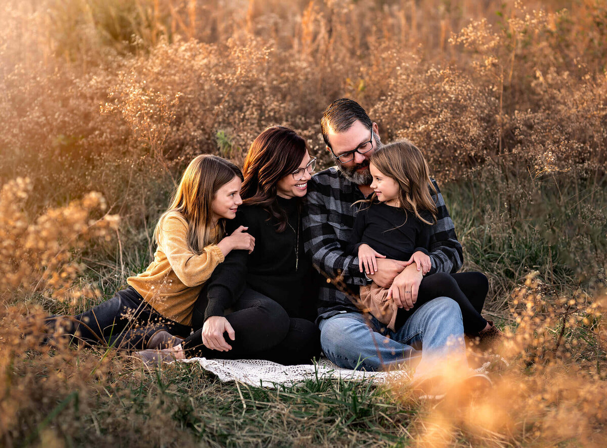A mom , dad and their 2 daughters snuggling on a blanket during their photo session with an Asheville Family Photographer