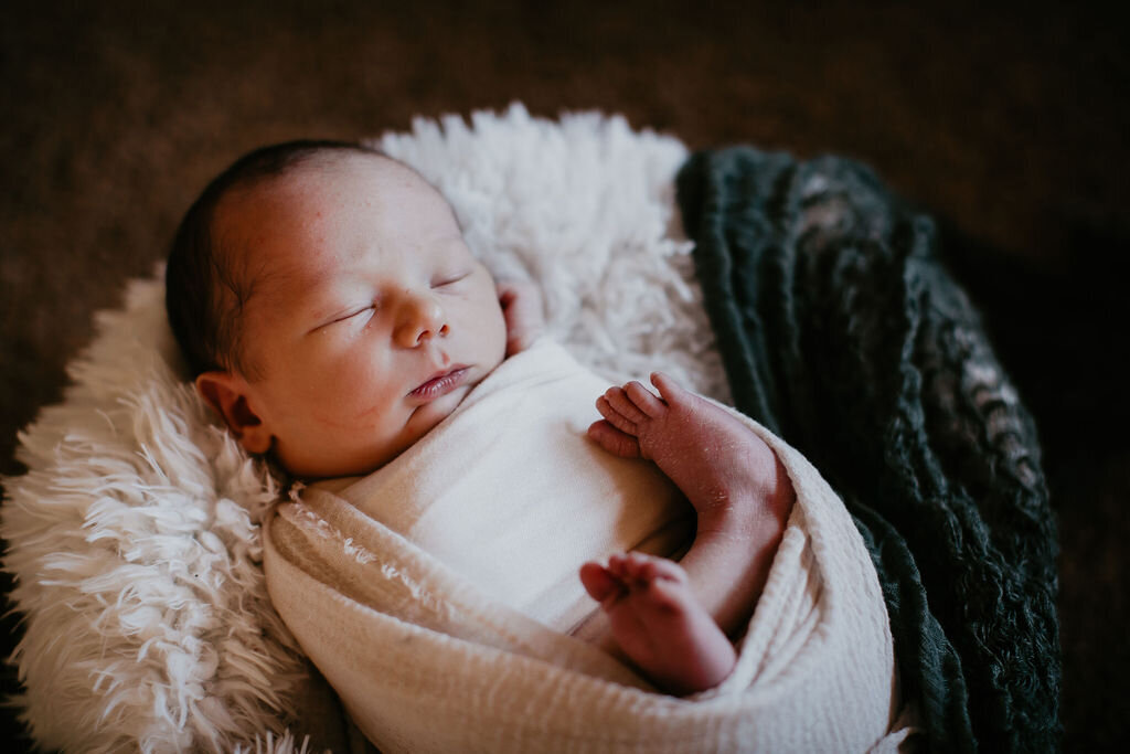 A newborn baby snuggled up in a blanket