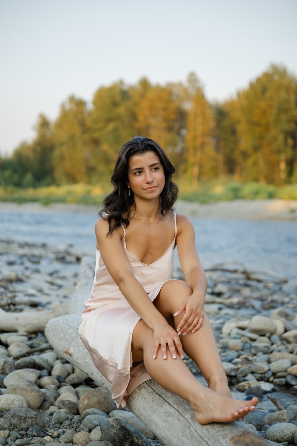 high school senior girl posing on fallen log at river in snohomish