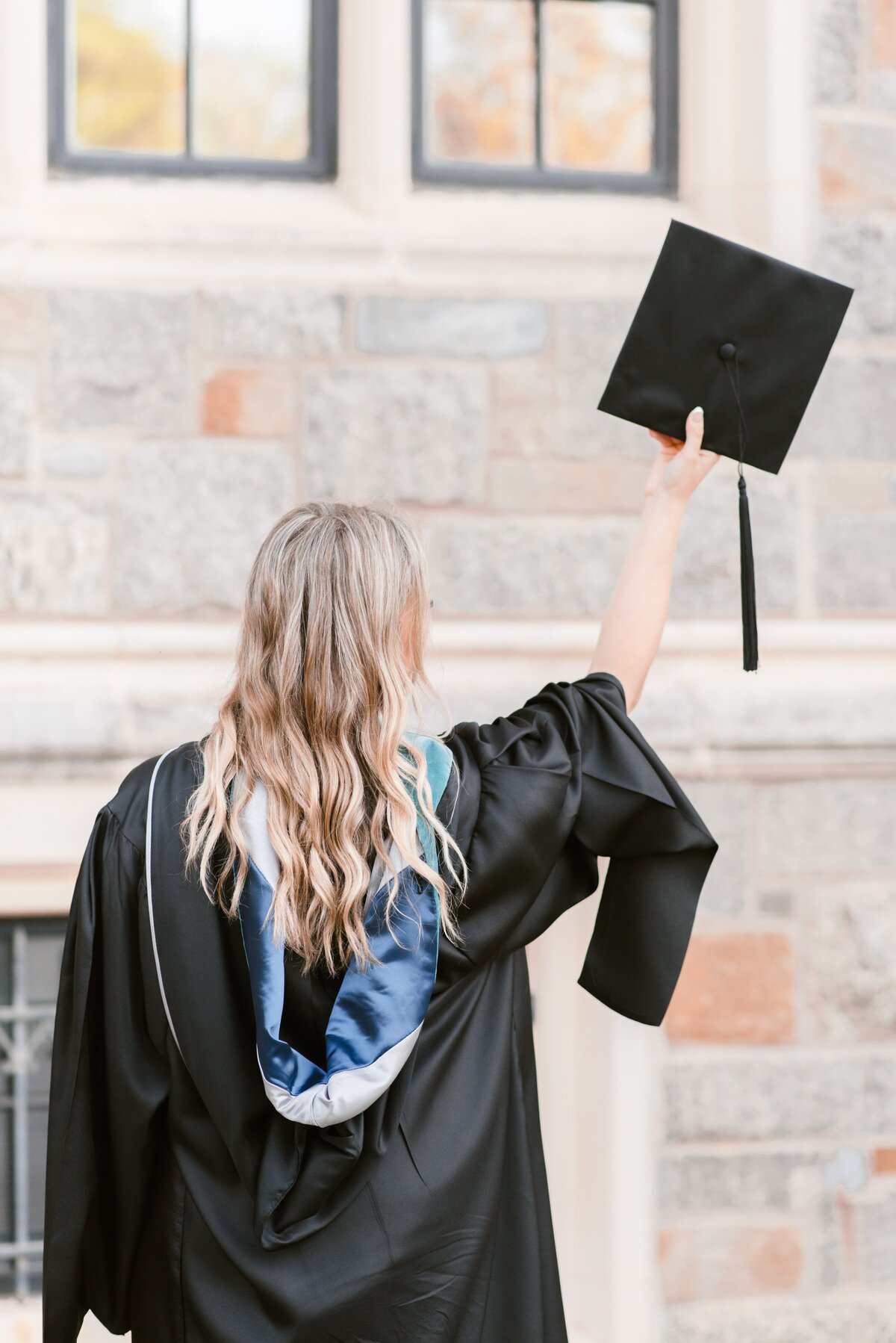 grad blonde female holding cap