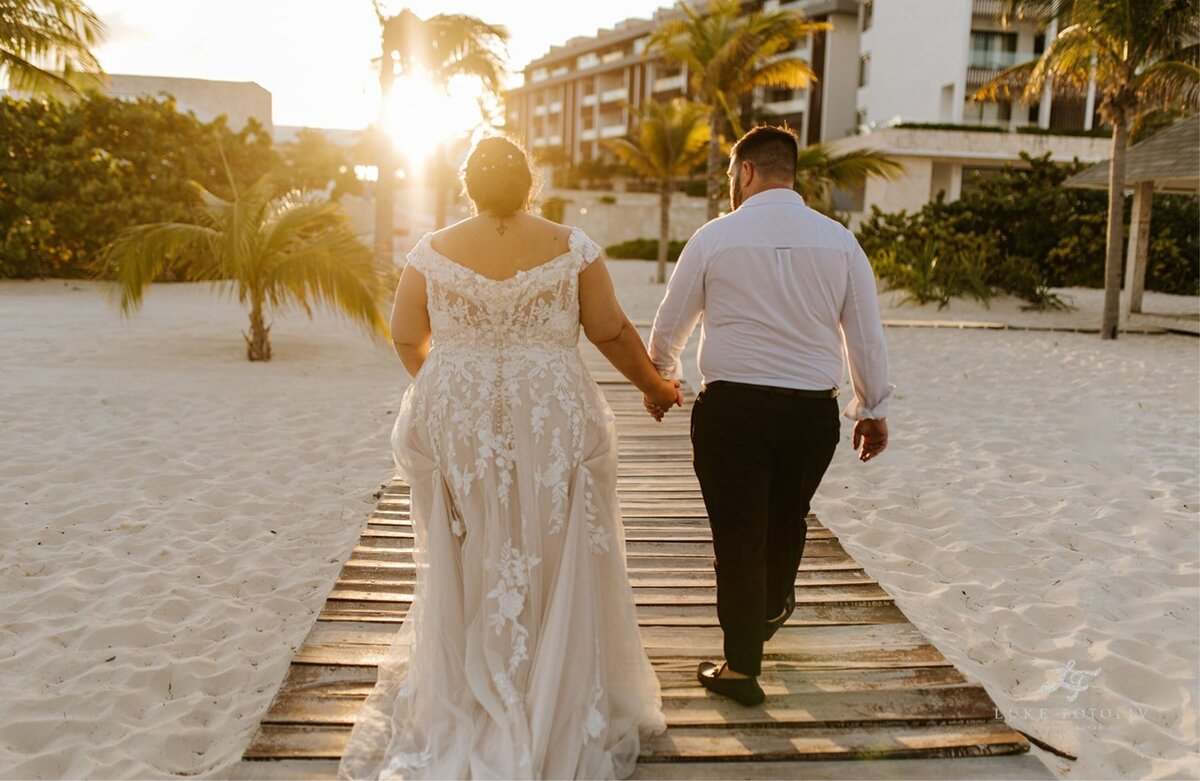 Couple walking down the aisle into the sunset at their beach destination wedding