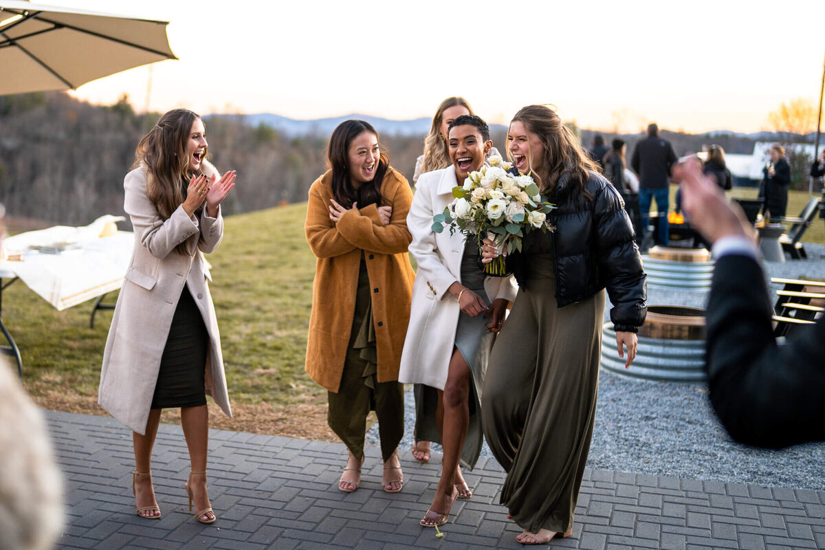 Bridesmaid smiles and cheers after catching the bouquet during a bouquet toss at a wedding in Ashville NC