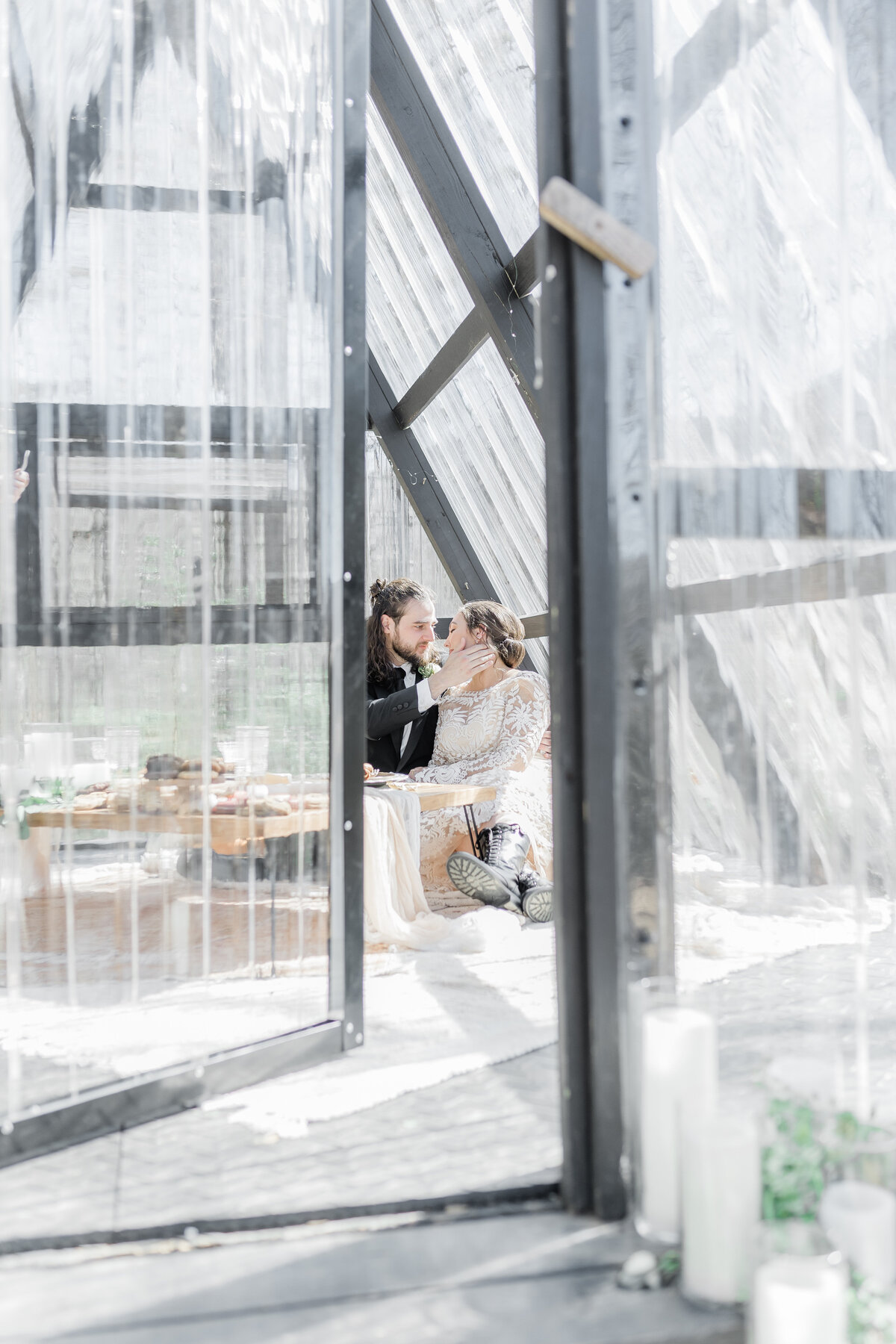 couple enjoying a picnic on their wedding day in a glass a-frame cabin in the mountains.