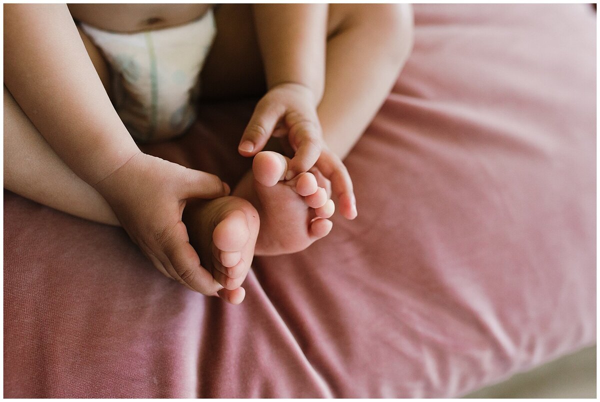 Toes of a toddler child sitting on pink velvet sofa