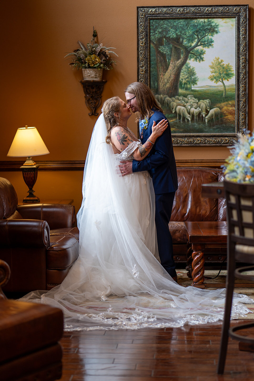 Wedding bride and groom in a moody lit room by a window in front of a lamp and a picture on the wall