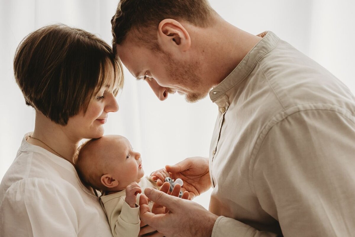 mother and father gazing lovingly at their newborn baby. Heartwarming newborn photography by Ruaa Hamdan in Altrincham, UK.