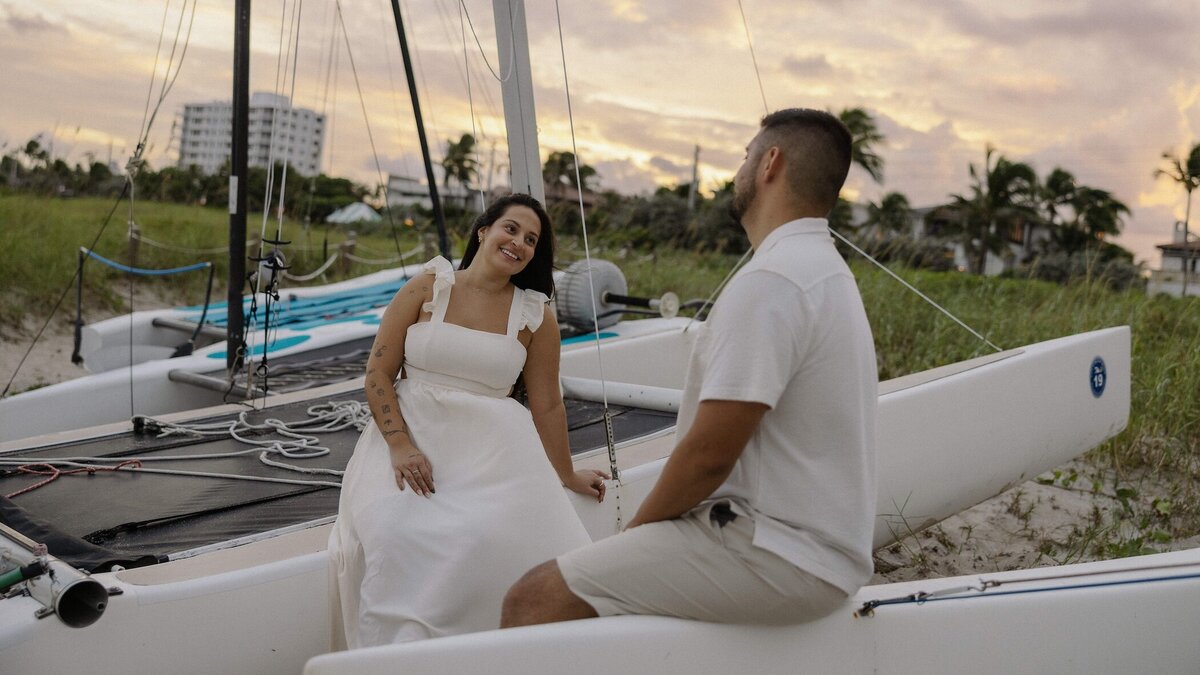 couple sits on sail boat on the beach