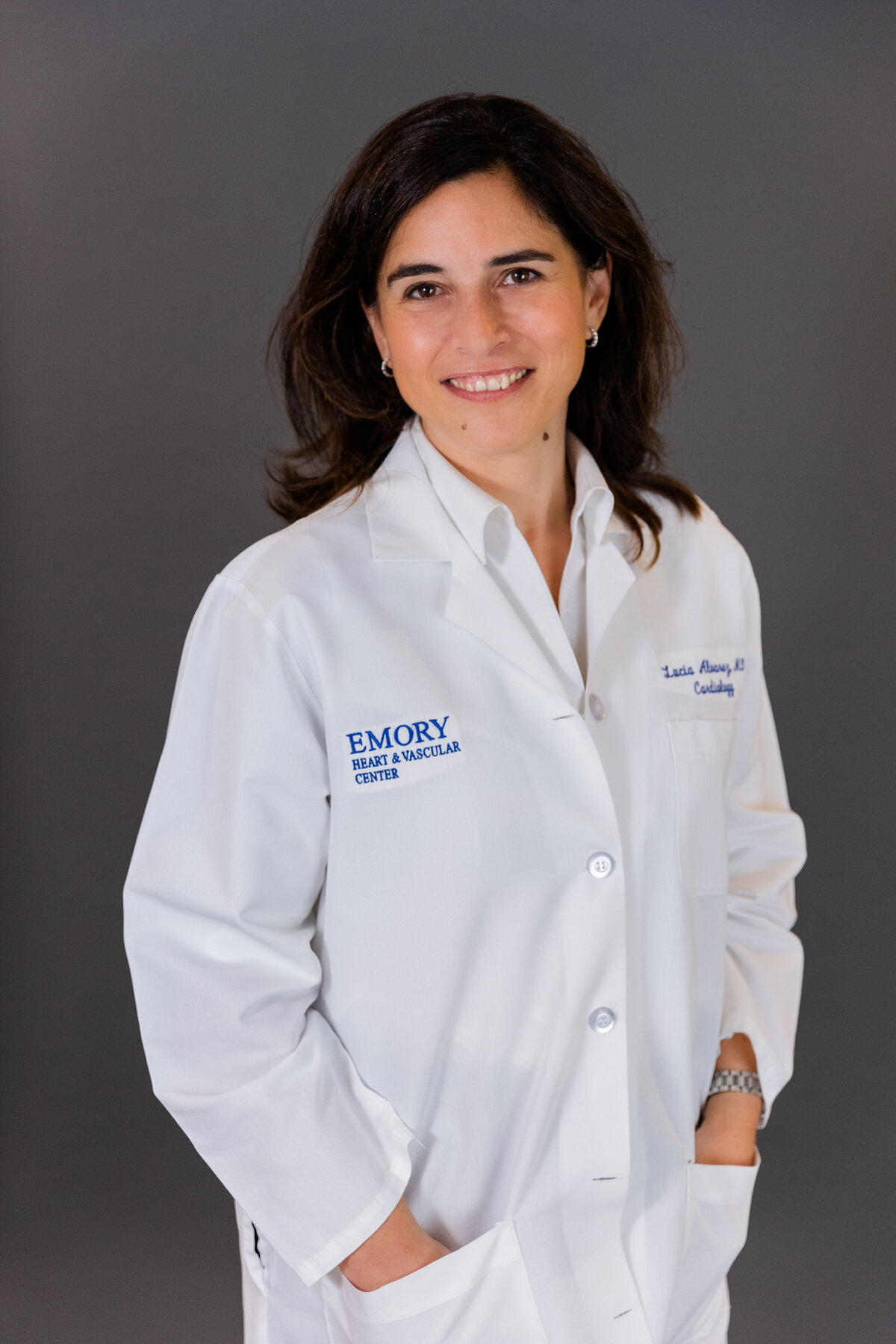 doctor wearing a white blouse hands in pockets in front of a dark gray backdrop in studio during portraits