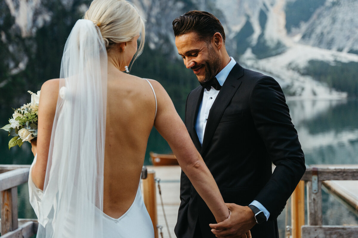 Bride and groom holding hands on wooden dock with mountain backdrop