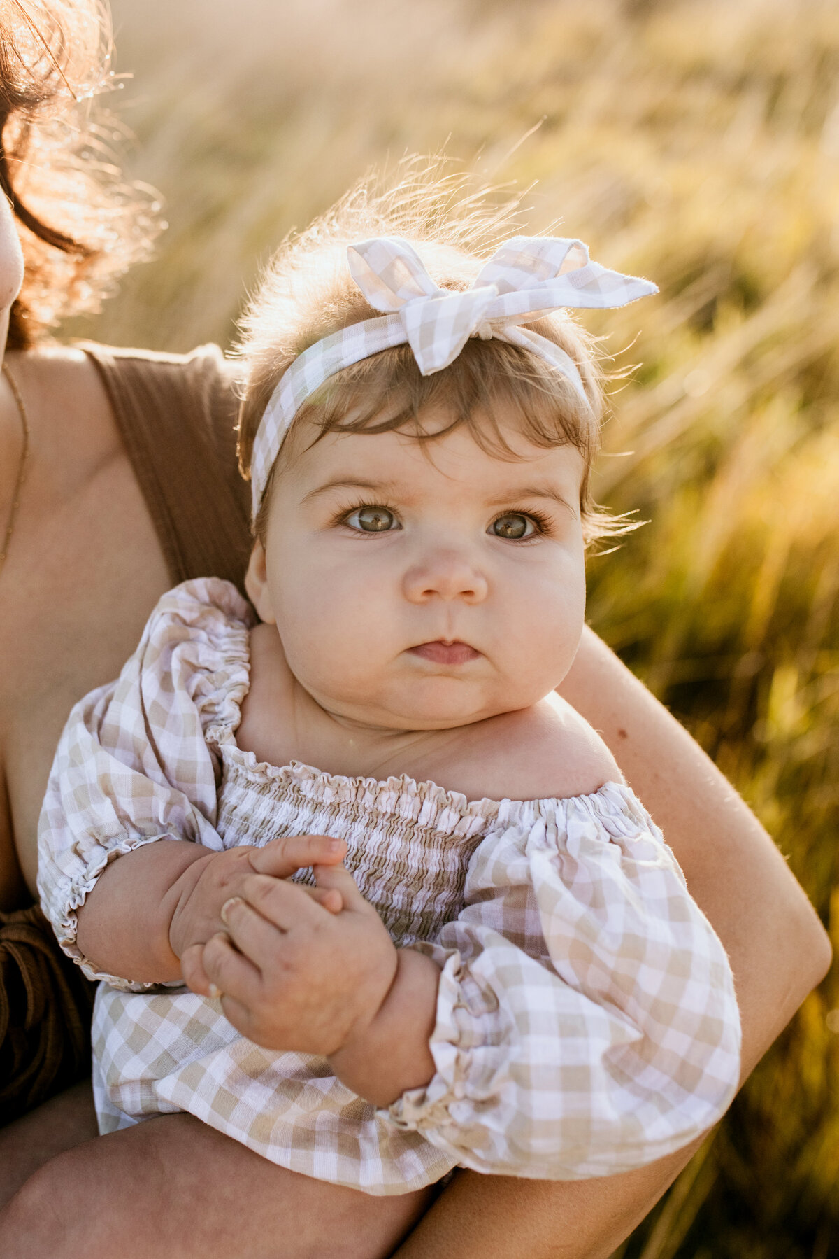 Cute baby with a bow on her head in a checker outfit. 