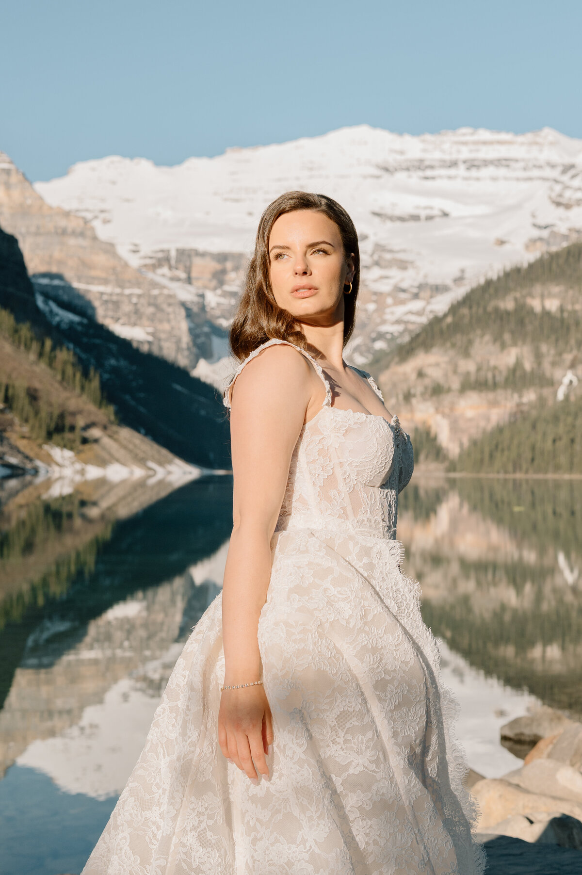 Detailed lace wedding dress by the lake with reflections