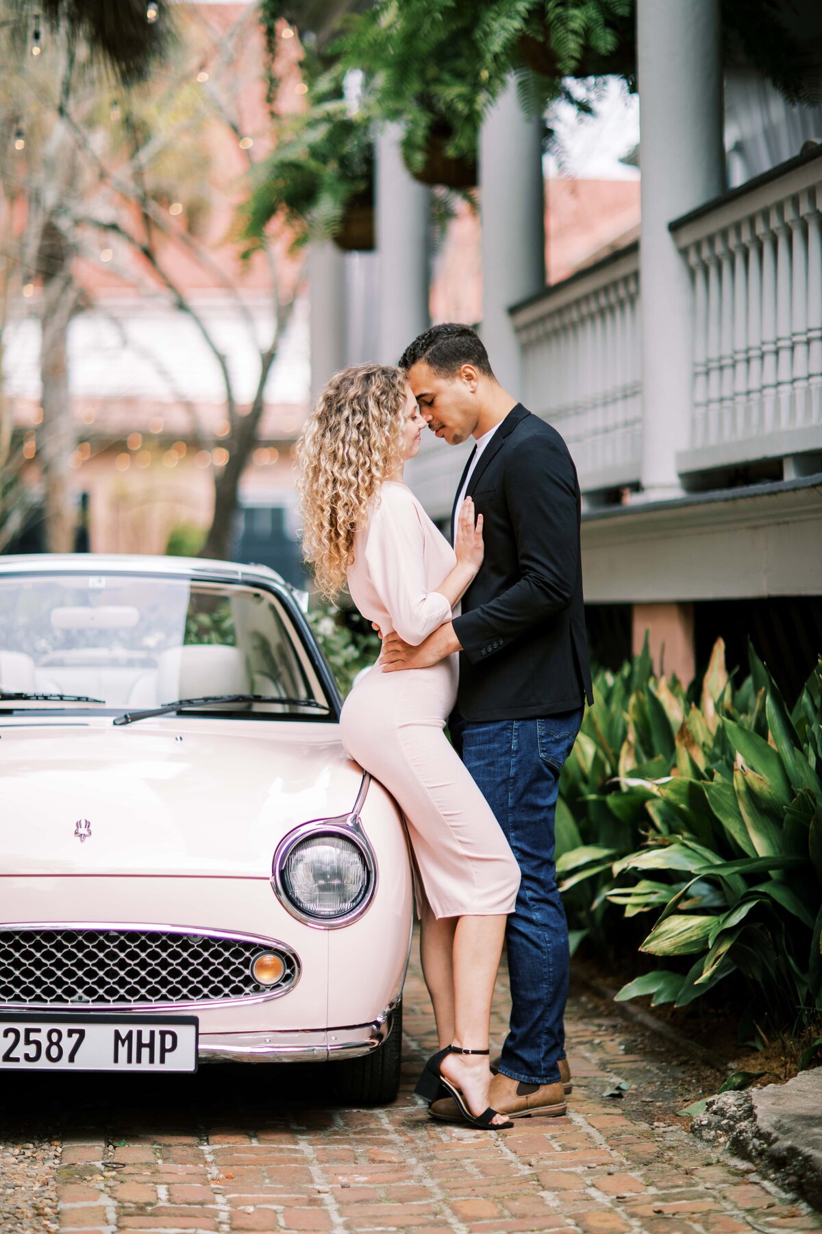Couple sitting beside Charleston car The Pink Figgy during engagement session with Danielle Defayette Photography