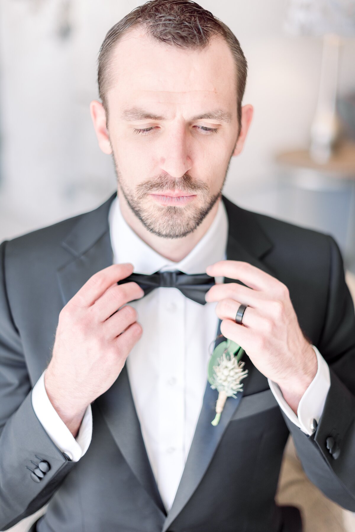 groom getting ready the day of his wedding and adjusting his tie