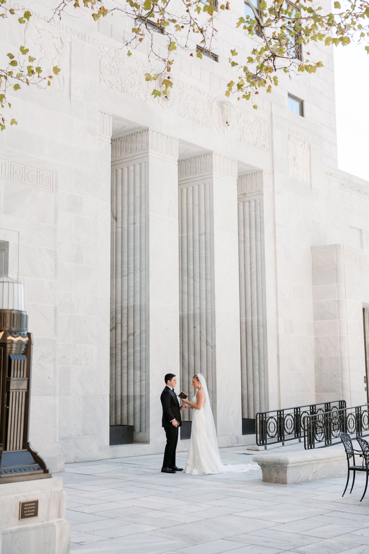 Wide shot of bride and groom sharing vows in front of grand white marble columns in Philadelphia.