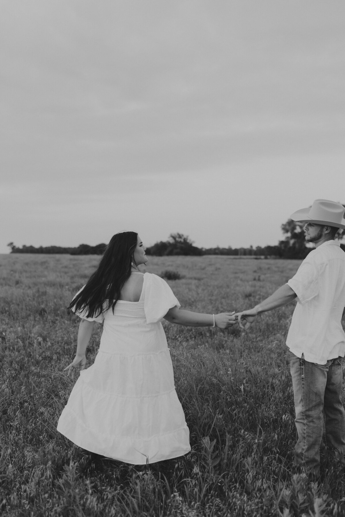 couple dancing in field in black and white photo, couple posing ideas and cowboy hat photoshoot ideas