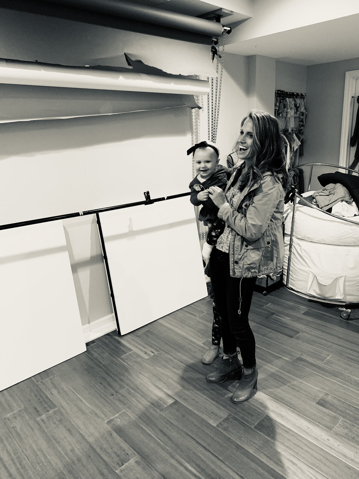 Mom and daughter smile excitedly looking at pictures on the wall of first birthday in Greensburg studio.