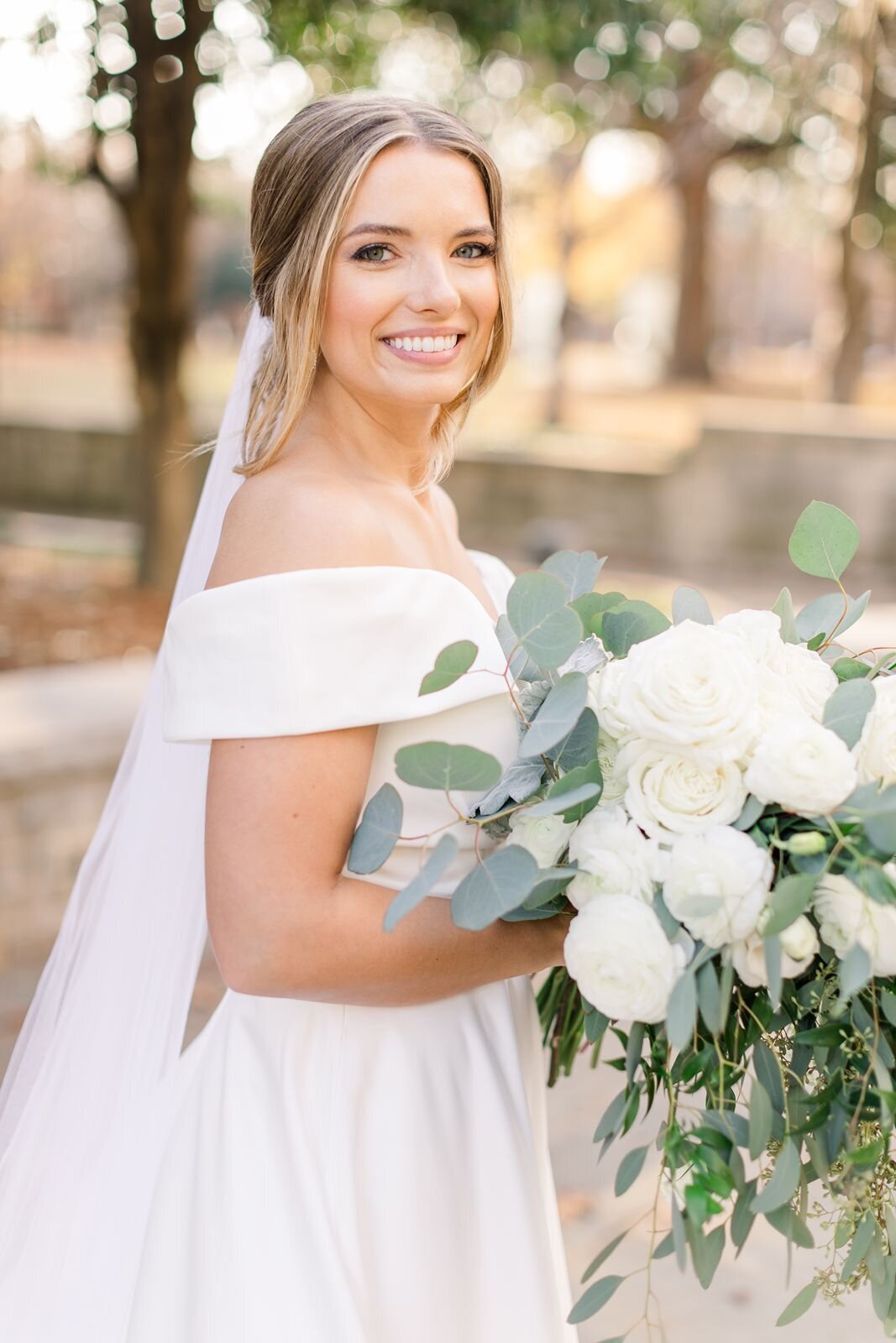 Stunning bride holds white floral and eucalyptus wedding bouquet