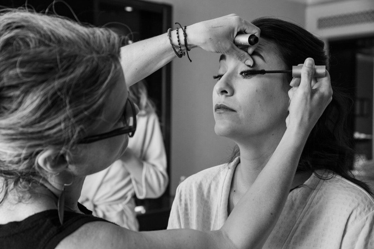 A black and white photo of a woman getting her makeup done