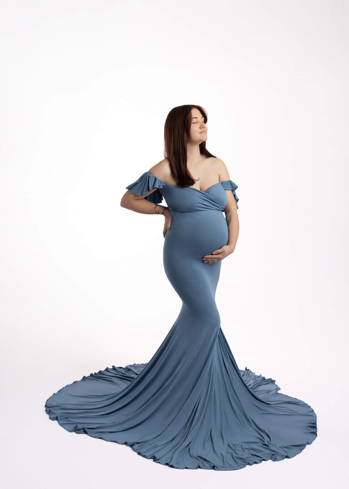 pregnant woman holding her belly wearing a blue dress
