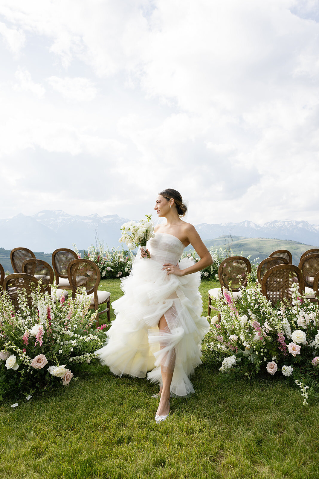 fashion forward bride poses in front of ceremony aisle with the Tetons of Jackson Hole in the background