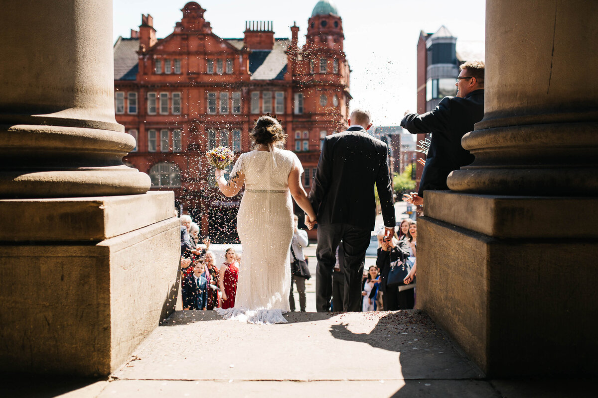 a wedding couple walking down the steps at leeds civic hall
