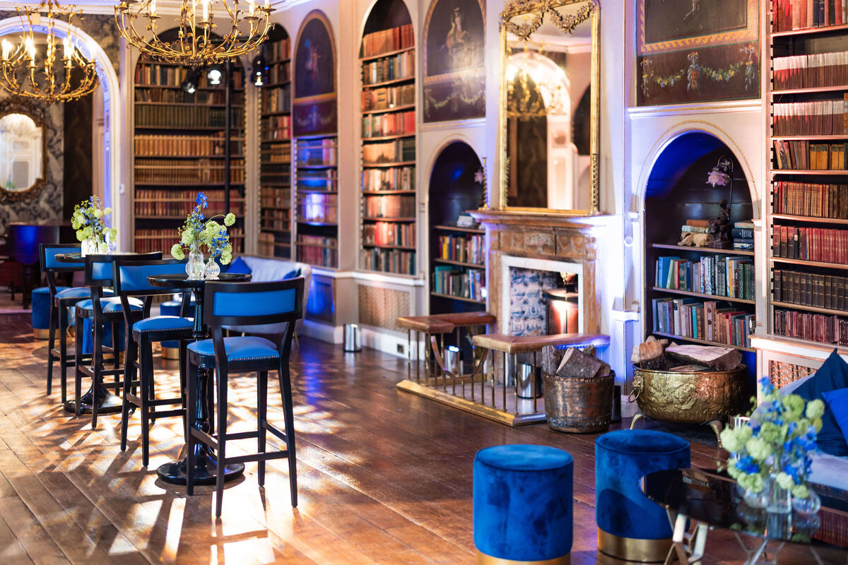 avington park’s library set up with blue lounge furniture and blue bar stools at poseur tables for a drinks reception at a 50th birthday party