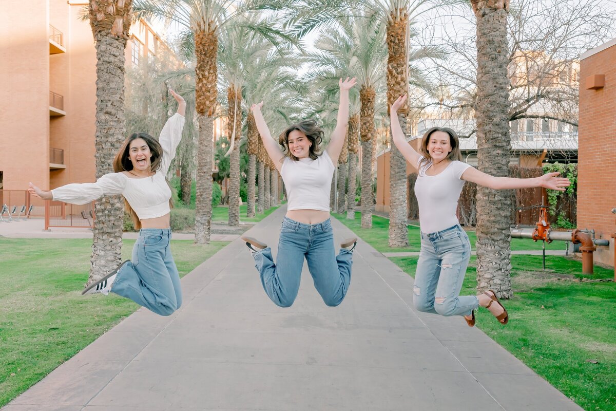 3 senior girl friend jumping for joy on Palm Walk at ASU