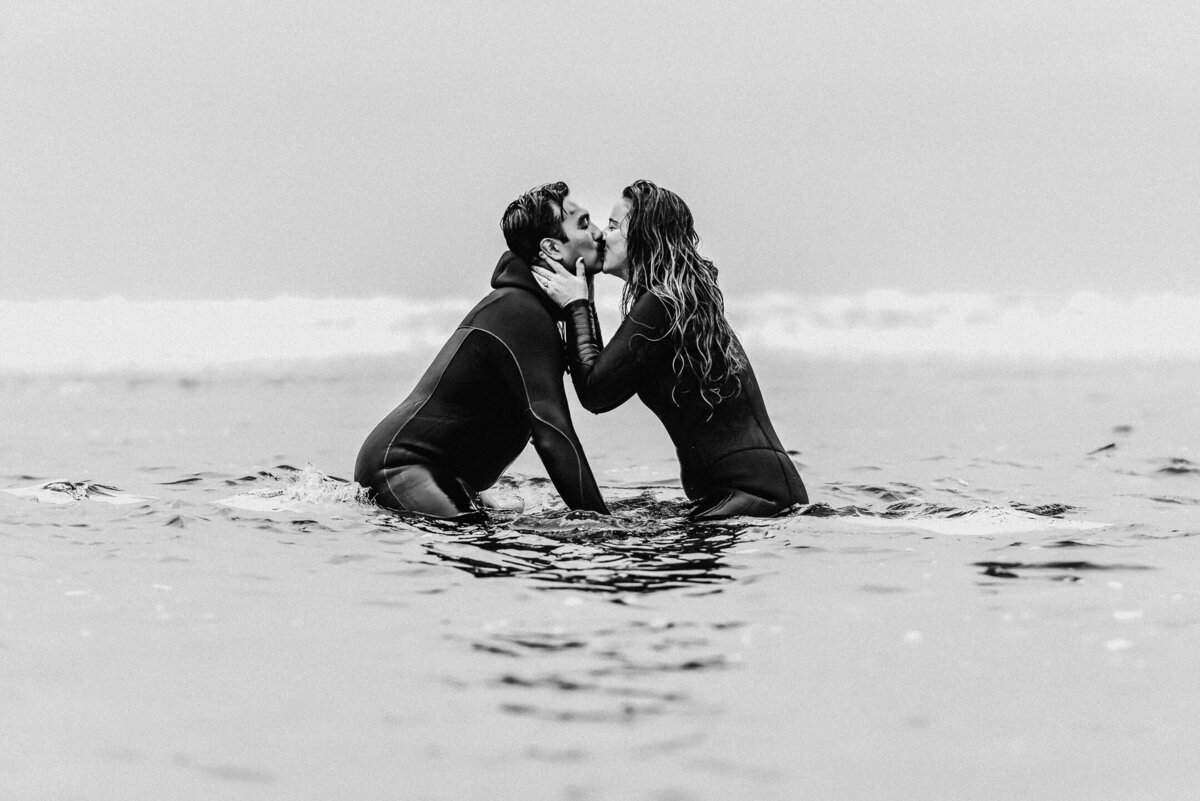 a couple kissees while floating out on their surf boards in the pacific for their Oregon coast elopement