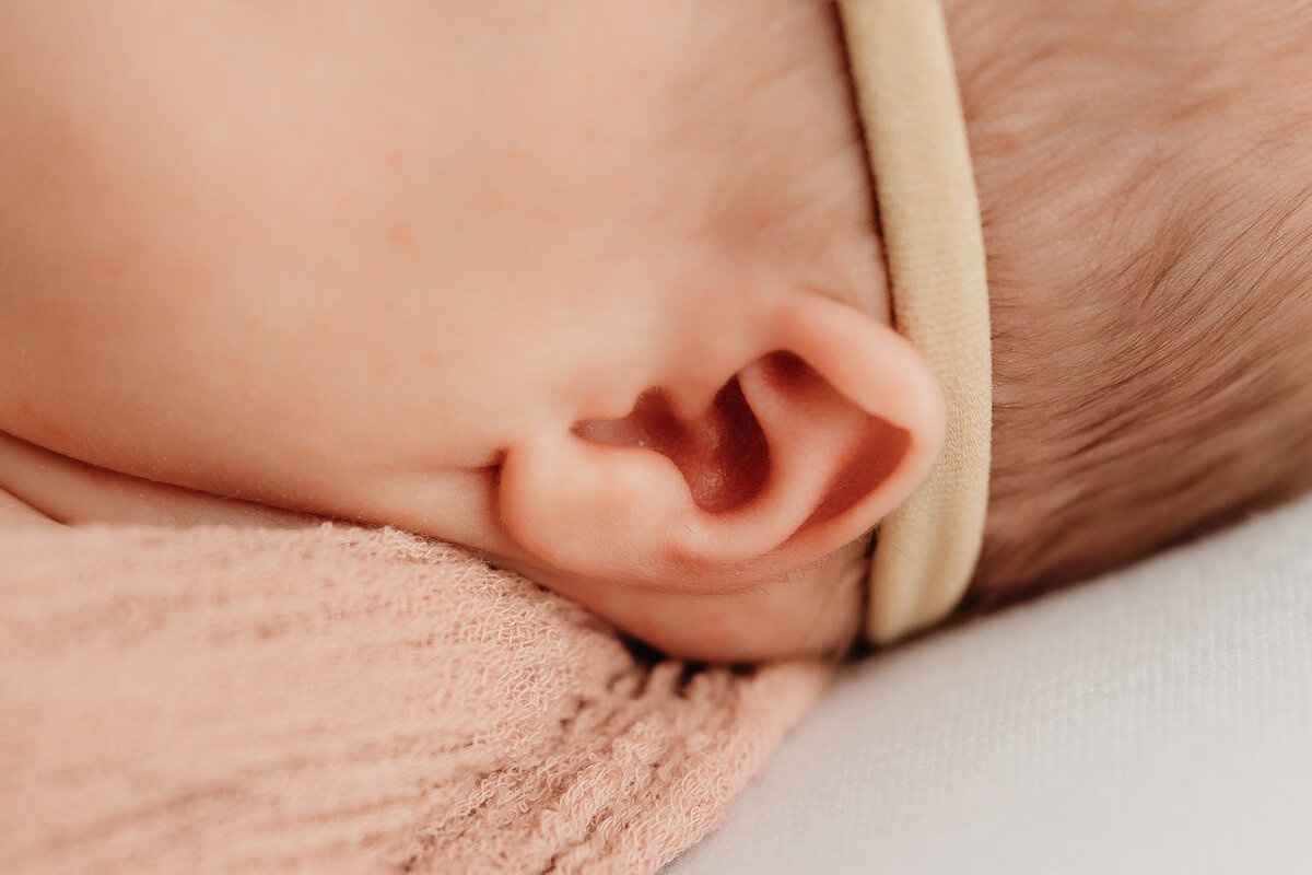 Close-up image of a newborn baby’s ear wrapped in a soft blanket, captured in a detailed newborn session by Mary Wiebe Photography.