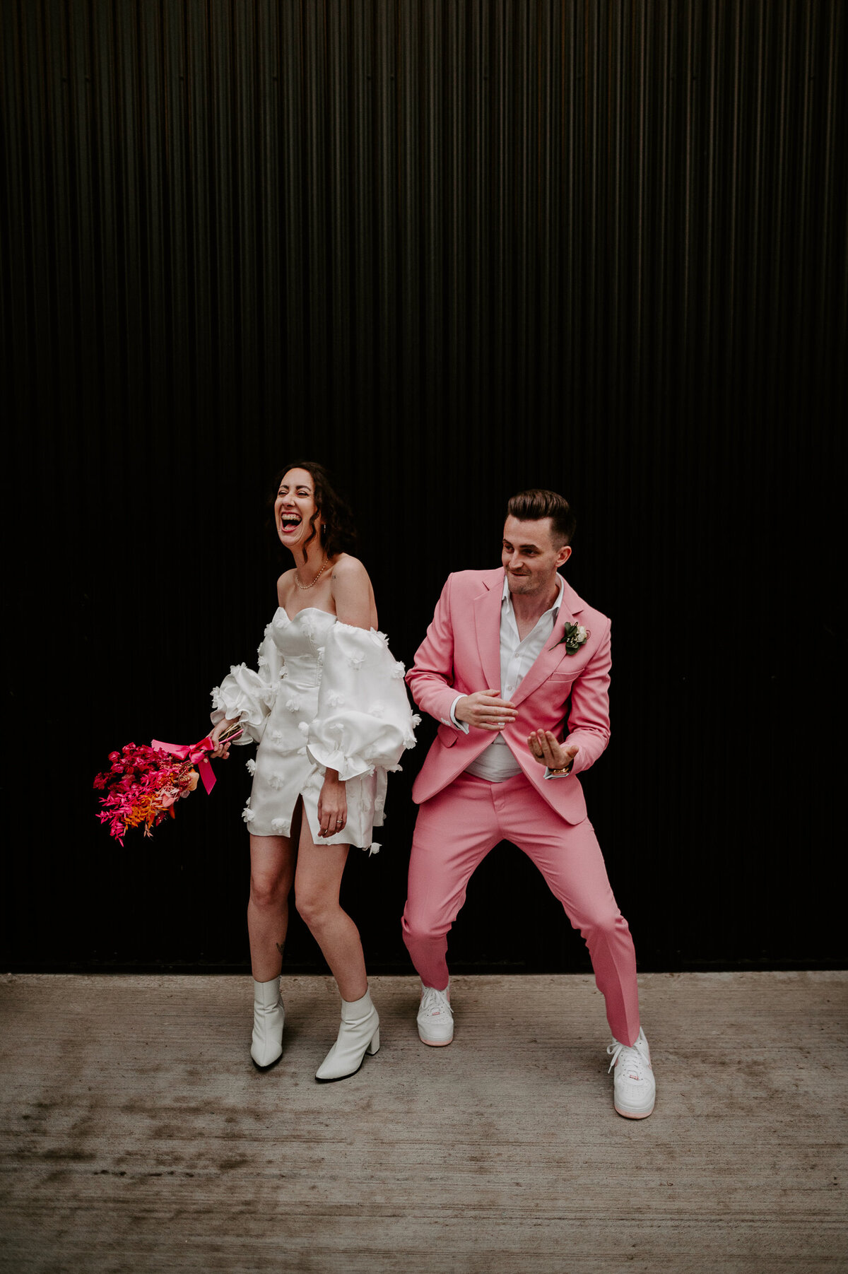 Bride in a short dress dances with a groom in a pink suit at The Shack Revolution