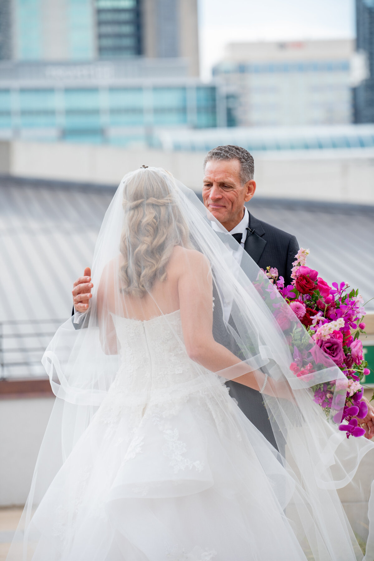 Eye-catching bright pink and fuchsia bridal bouquet composed of phalaenopsis and makara orchids, peonies, garden roses, and ranunculus. Design by Rosemary and Finch in Nashville, TN.