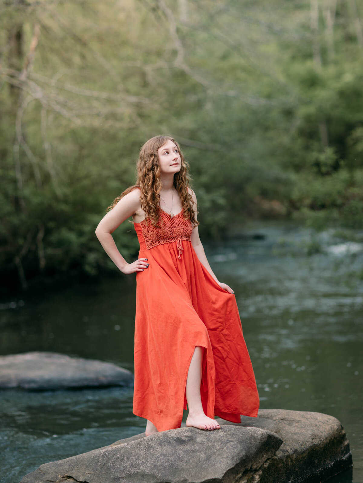 Enchanting senior portrait of a girl on a rock in the middle of the water of Line Creek in Peachtree City, Georgia.