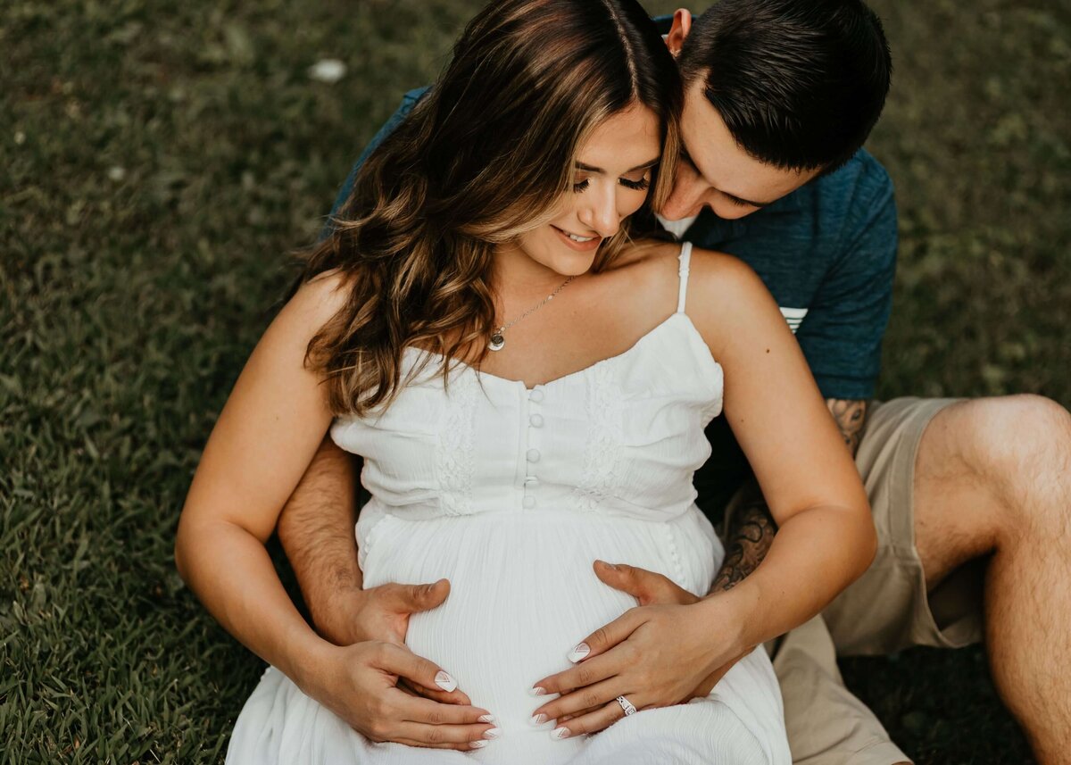 Pittsburgh maternity photographer captures couple embracing in grass during session.