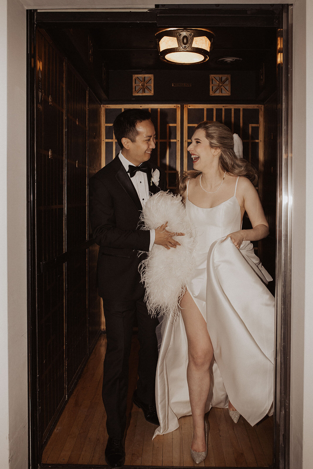 Newlyweds laughing in a vintage elevator.