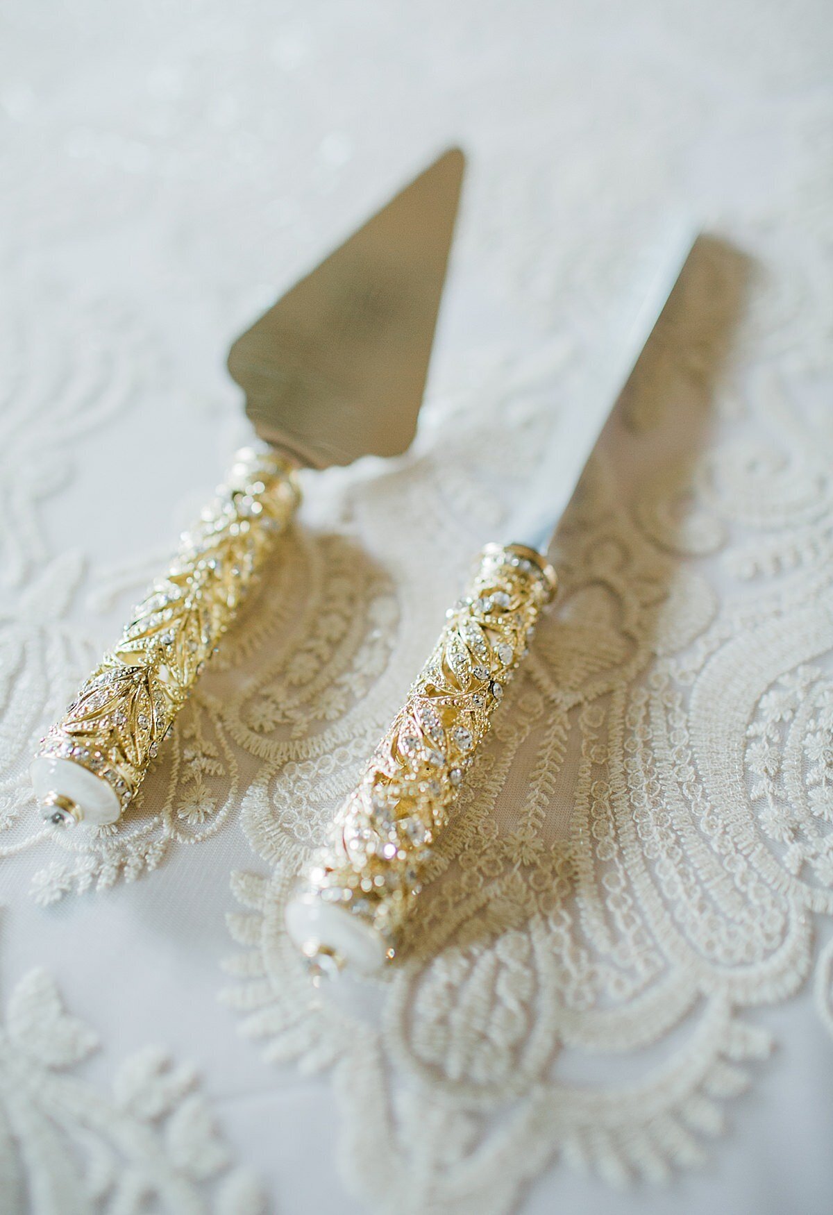 Gold and white filigree cake serving tools on a white lace table cloth.