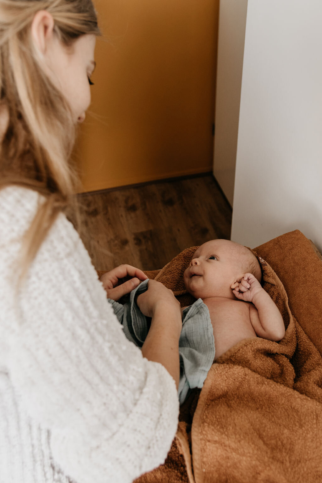 Moeder kleed newborn baby aan tijdens de newbornshoot