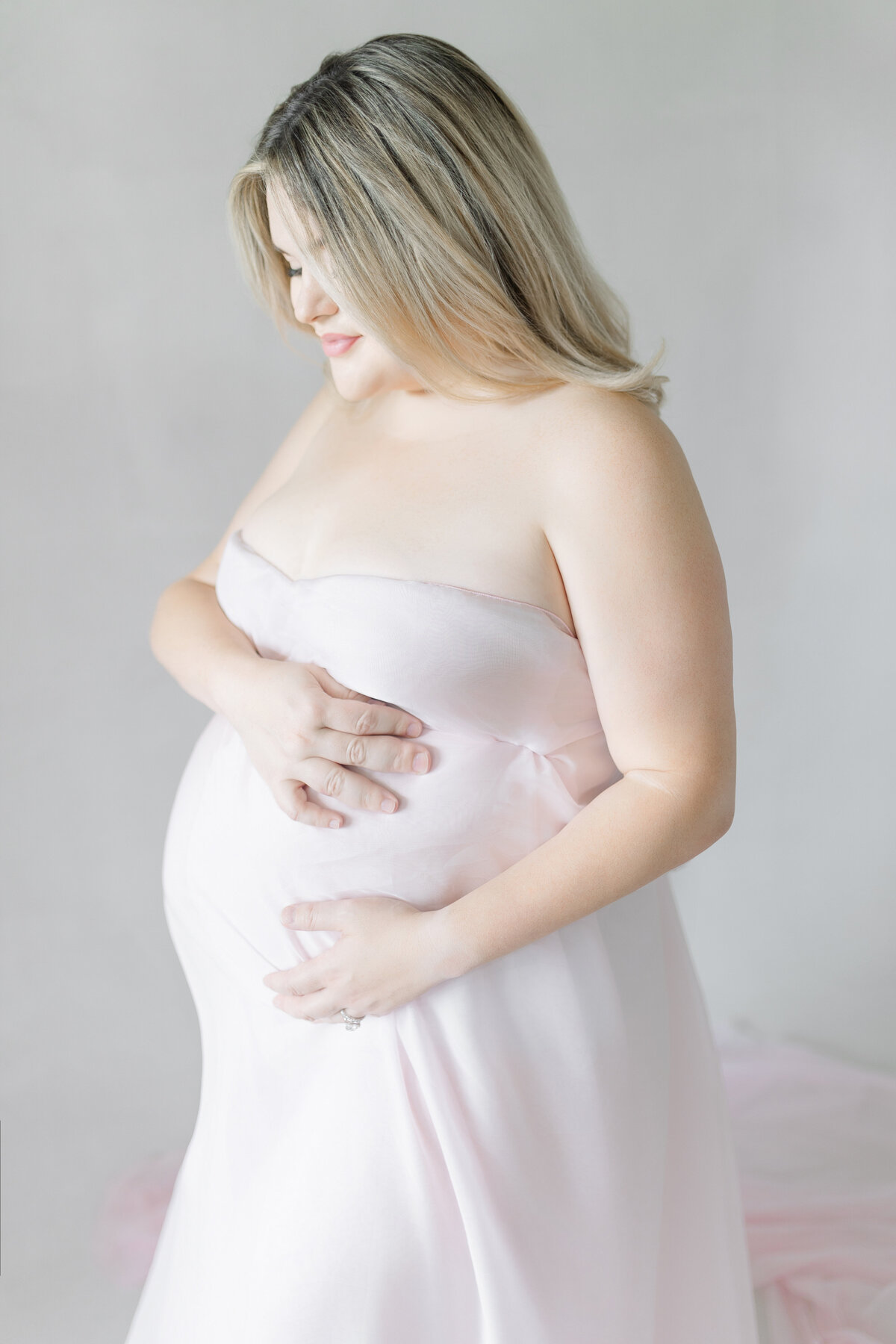 Luxury maternity portrait of Calli in soft blush gown, captured in natural light Tampa studio