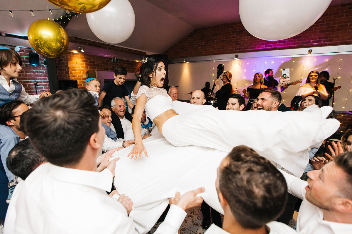 Jewish Bride being thrown up in the air during Hora looking rather fearful