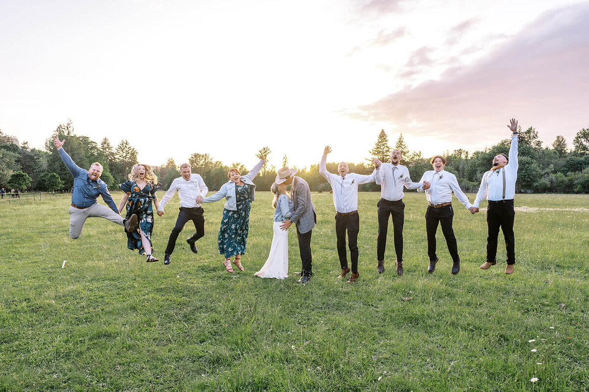 A group of people jump into the air celebrating while a bride and groom kiss.