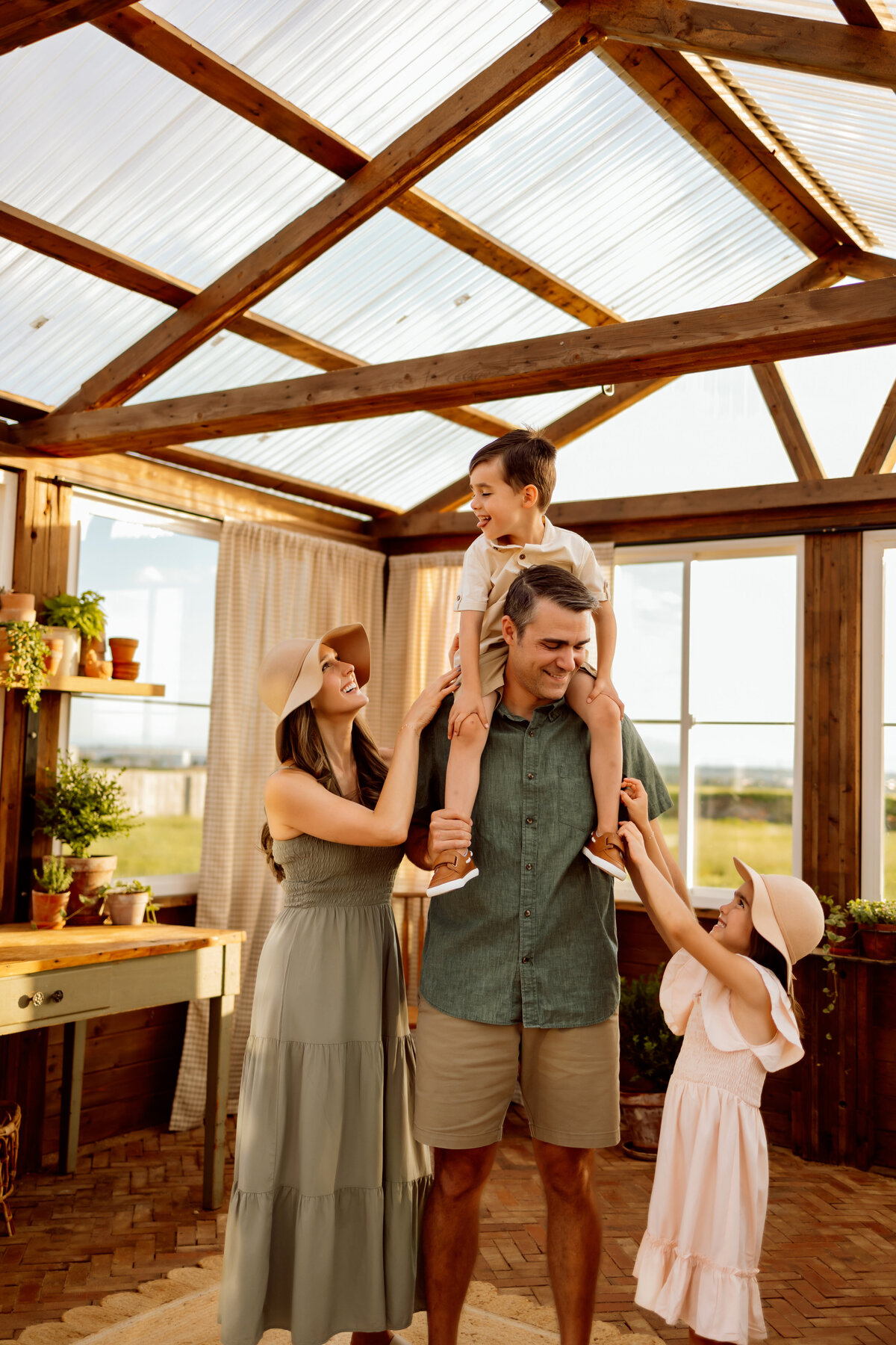 Family of four has fun in a green house laughing and smiling for their Denver family photo session