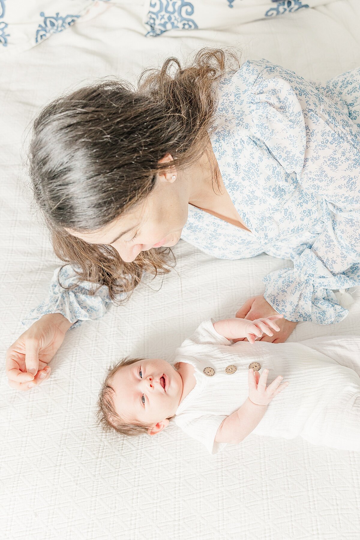 Mom lays on bed dung in-home newborn photo session with Sara Sniderman Photography in Needham Massachusetts