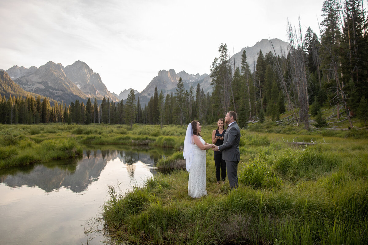 A couple stand facing each other and holding hands during their elopement ceremony in Idaho.