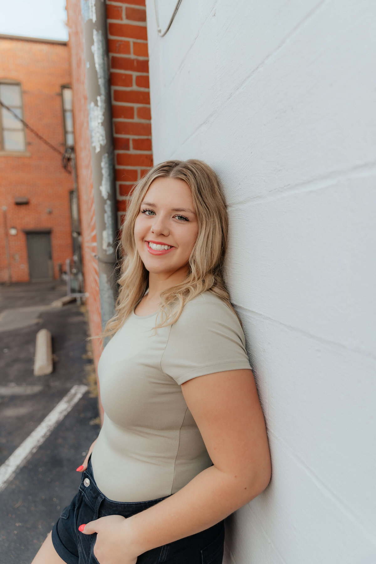 High school senior smiling in casual outfit against city wall, modern Ohio senior portraits for grads who want photos that feel authentic and fun